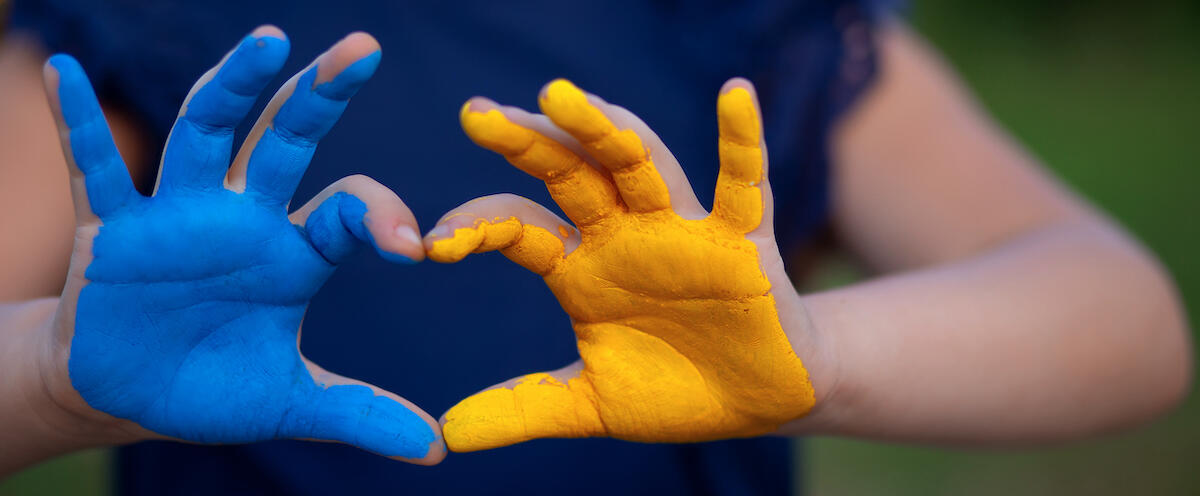 Child's hands, one painted blue and one gold, in shape of a heart